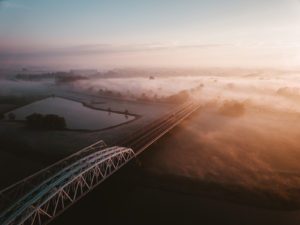 Spoor- en autobrug over rivier bij Arnhem, ochtend zon, nevel