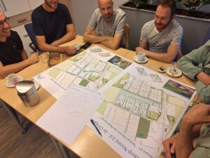 Inwoners van Elsendorp met elkaar in gesprek rond een tafel waarop kaarten met verschillende stedenbouwkundige varianten liggen